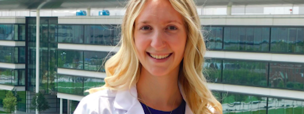 Kelsey White in her whitecoat in front of a hospital building