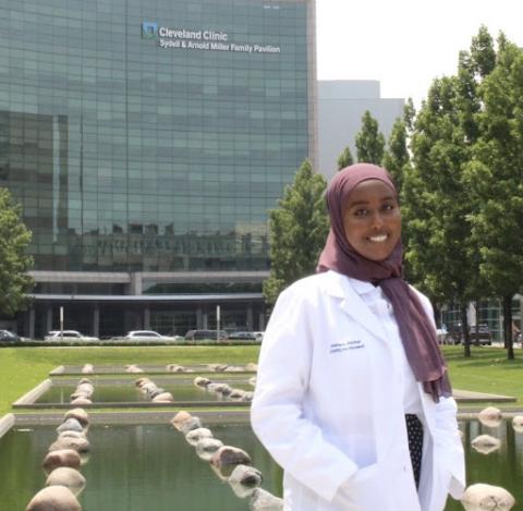 Asma Abukar in her whitecoat in front of a hospital 