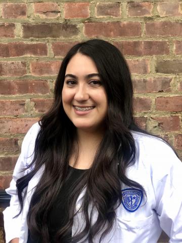 Jessica Miccio in her whitecoat in front of a brick wall