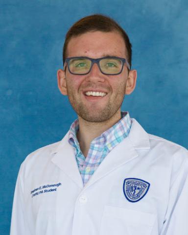 Stephen McDonough whitecoat headshot in front of a blue background