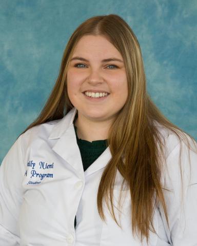 Emily Niemi headshot in her whitecoat in front of a blue background