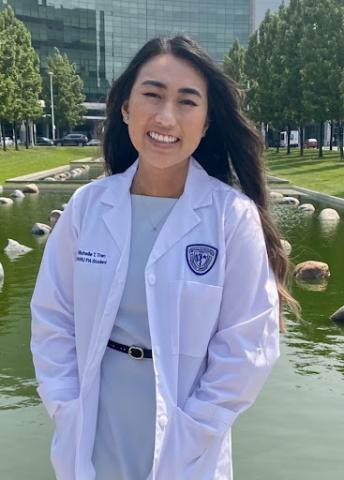 Michelle Tran in her whitecoat in front of a hospital building