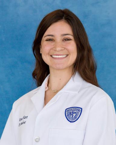 Rose Hart in her whitecoat headshot in front of a blue background