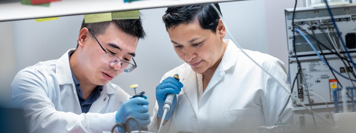 Male and Female researcher using pipet in lab 