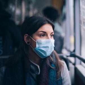 A person riding a bus with a facemask