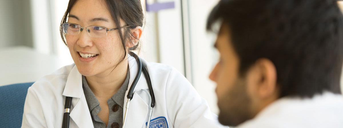 Two medication students in lab coats talking