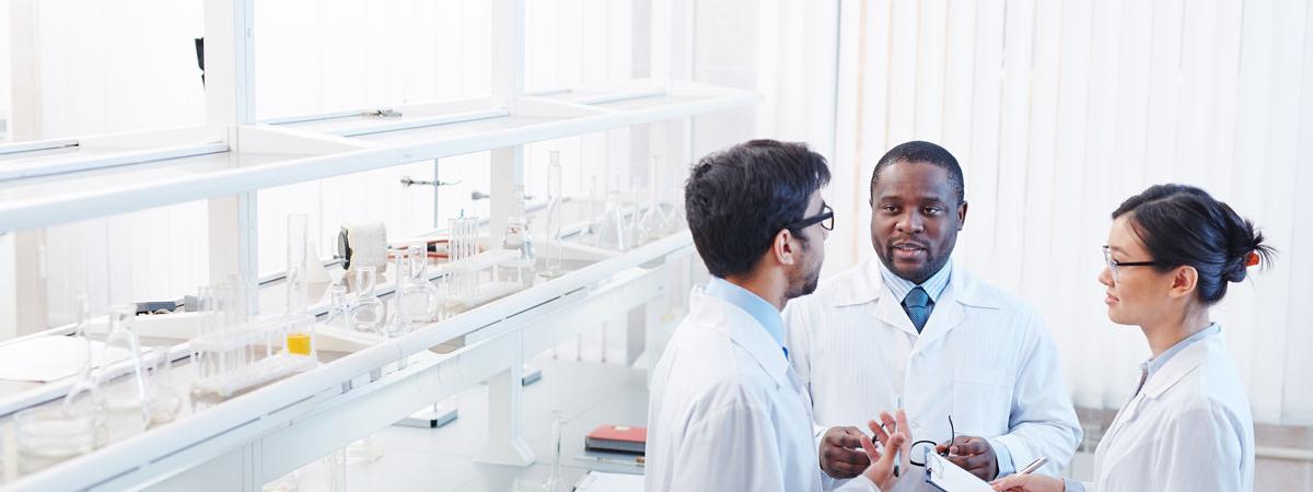 Clinical researchers talking in a lab next to lab equipment 