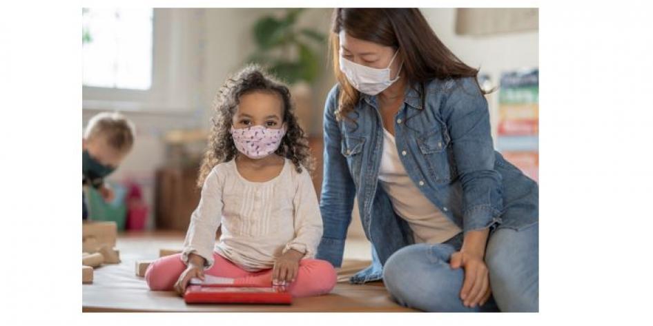 Small child and child care worker both wearing masks