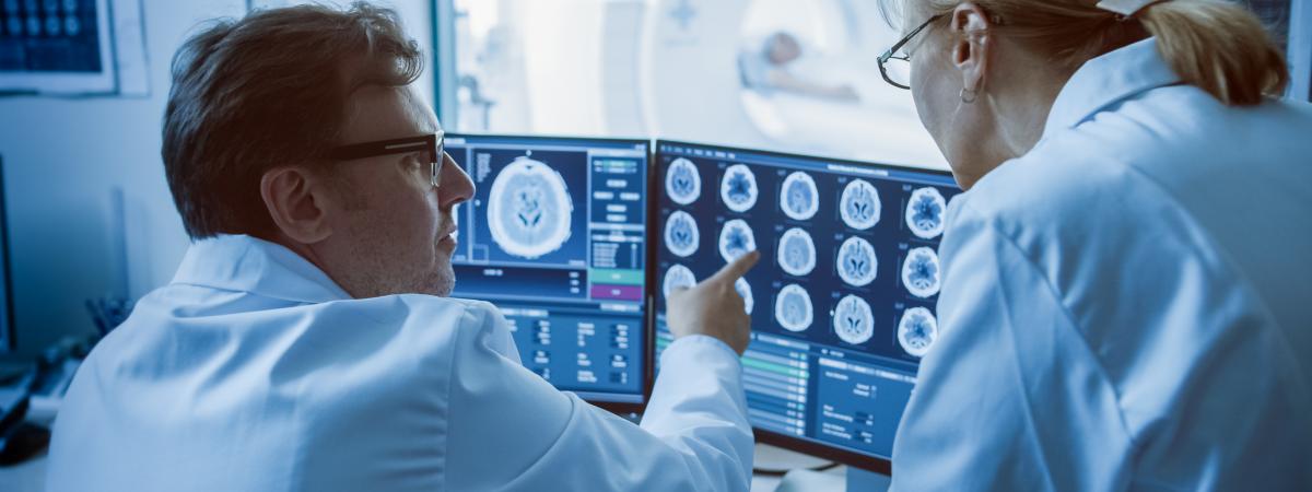 Two doctors review brain scans on computer screen