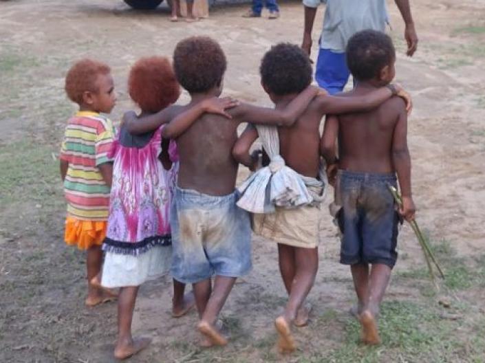 5 small barefoot children walking away in an outdoor setting in Papua New Guinea