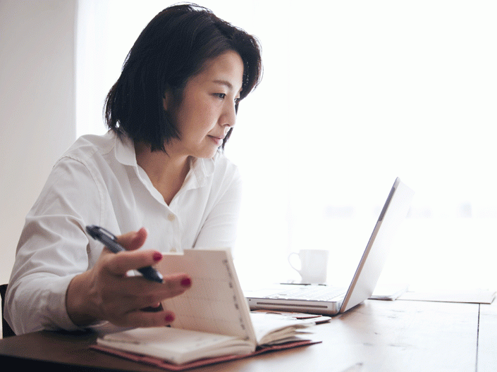 photo of woman, seated, looking at a laptop screen 