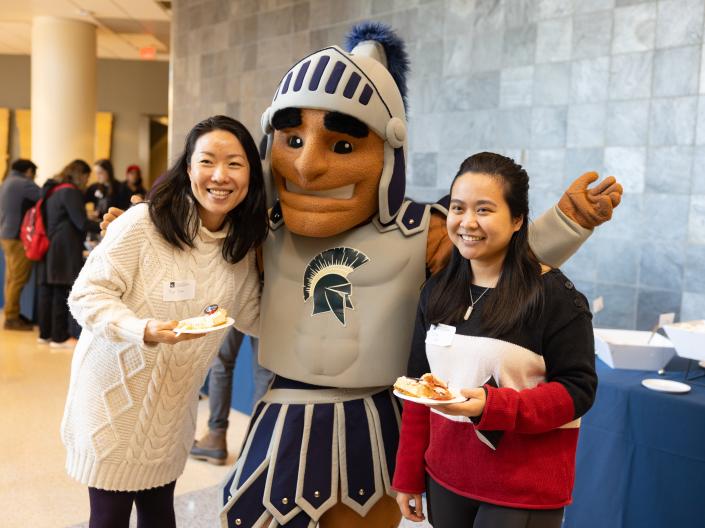 two students posing with Sparty 