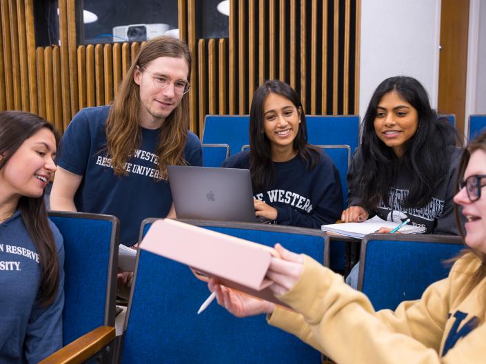 five students review material in a lecture hall