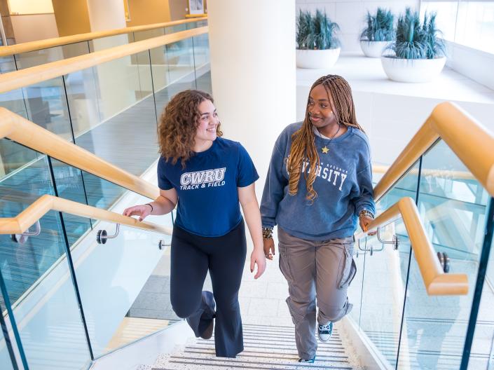 Two students walking up the stairs talking 