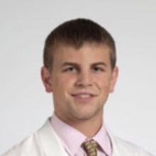 Headshot of Victor Kondray in white coat, tie, and white background