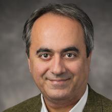 Headshot of Dr. Arash Kardan in dark tan jacket and white dress shirt