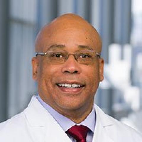 Headshot of Quinn Capers wearing a white doctor's coat