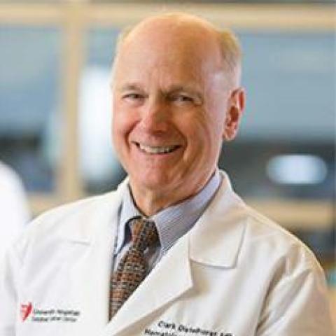 Man wearing white lab coat and tie smiling 