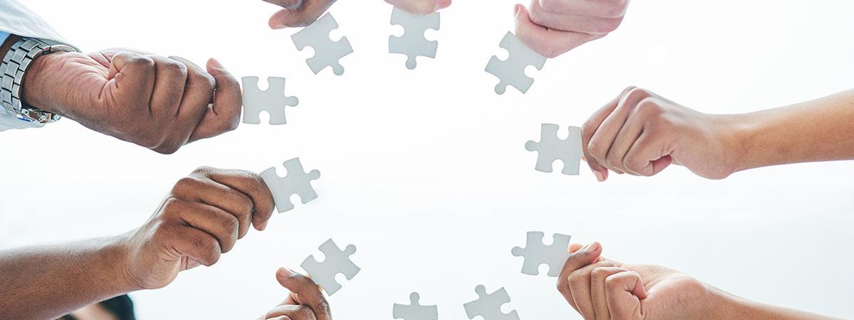 Close up of diverse group of hands holding puzzle pieces
