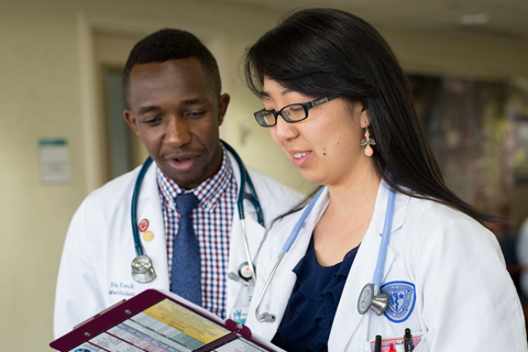 Two CWRU medical students in white coats in discussion on a clinical rotation