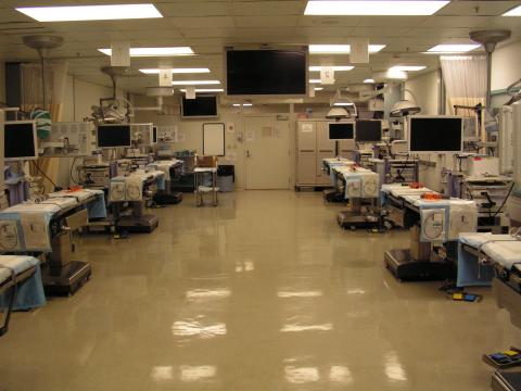 The Surgical Training and Research Lab space with a wide center hallway and four stations on either side with surgical tables, video towers, and integrated AV systems.