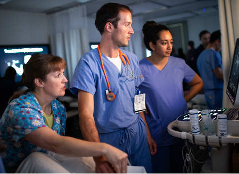 Three medical professionals looking at a monitor