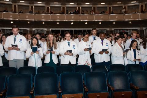 Students reciting the oath in their white coats 