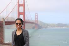 Syrena Bracey, MSTP student, standing in front of red suspension bridge