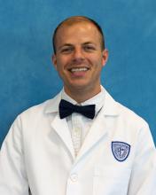 Man with short hair, a white coat, and a bowtie