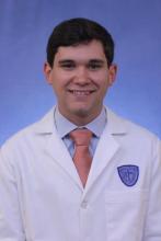 Male medical student smiling in white coat