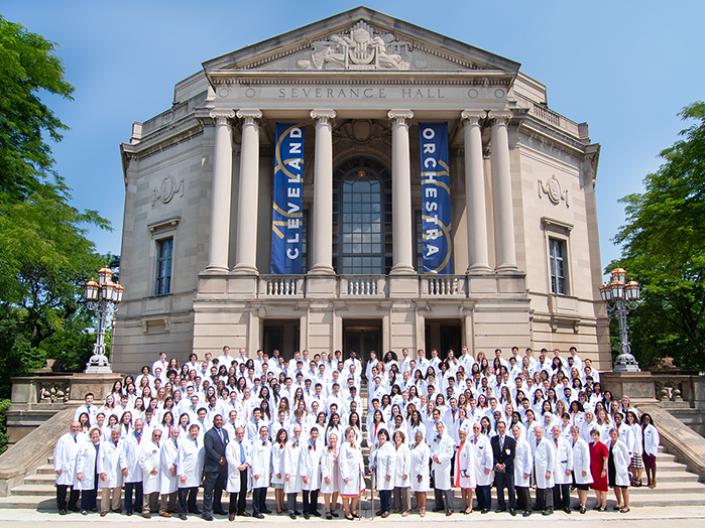 Large group of medical students in white coats standing in front of Cleveland's Severance Hall