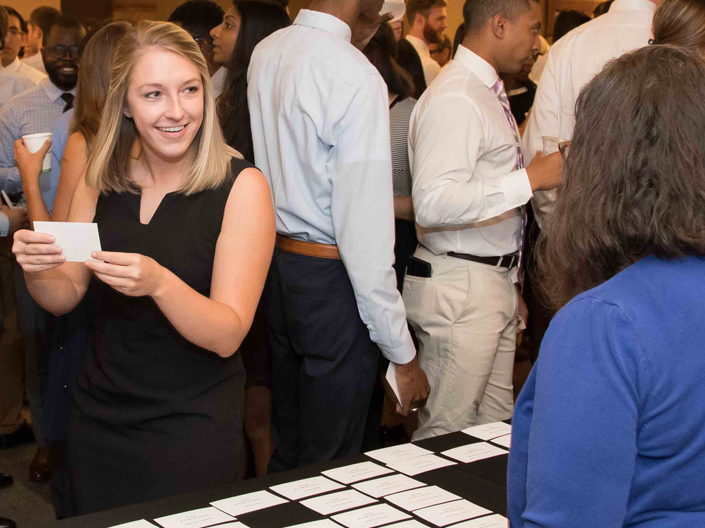 Woman in black dress leaves registration table with name card
