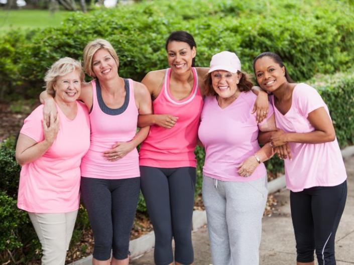 Five women in pink shirts pose together for a photo
