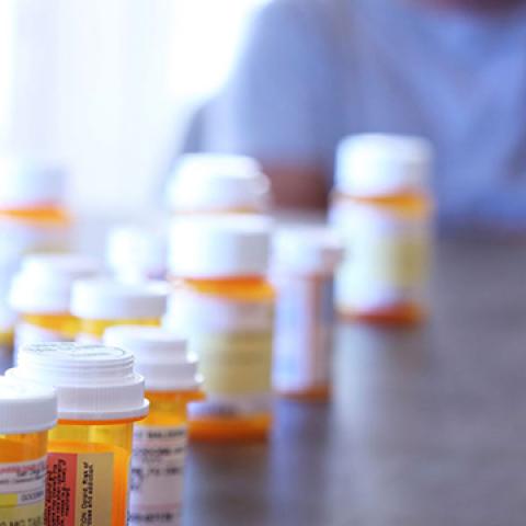 stock image of pill bottles on table and blurred person sitting near it