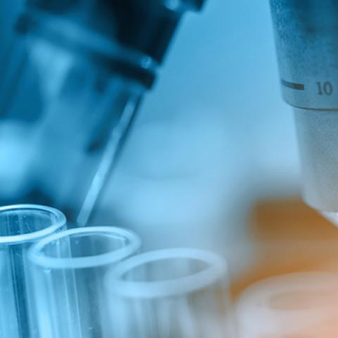 stock image of microscope and dropper with liquid going into test tube