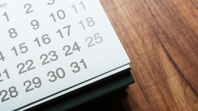 The corner of a desk calendar sitting on a wooden table