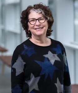 smiling woman with glasses and dark shirt with stars