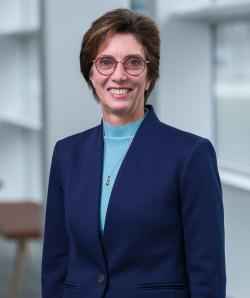 smiling woman with glasses and dark suit