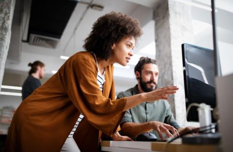 A man and woman looking at a computer screen.