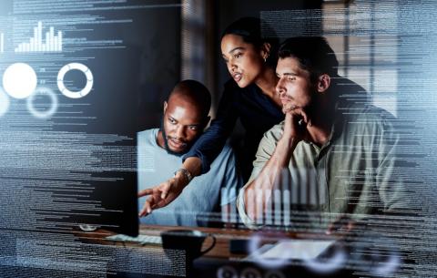 Two men and a woman looking at a computer in a darker room.