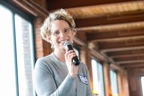 Woman smiling at the camera holding a microphone.