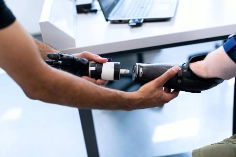 A close-up of someone assisting an individual install their bionic hand