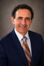 Dr. Anthony Atala; Male wearing a dark suit and striped tie, short curly hair