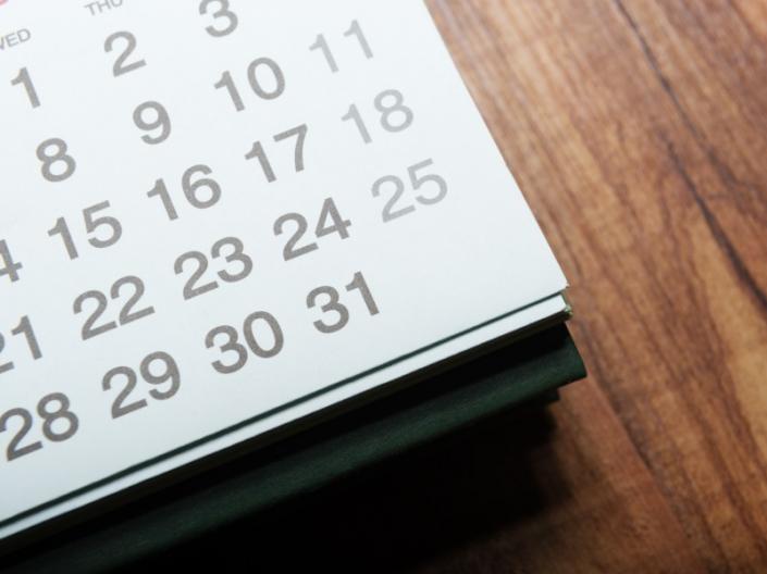 The corner of a desk calendar sitting on a wooden table