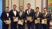 Group of men smiling with awards in suits.