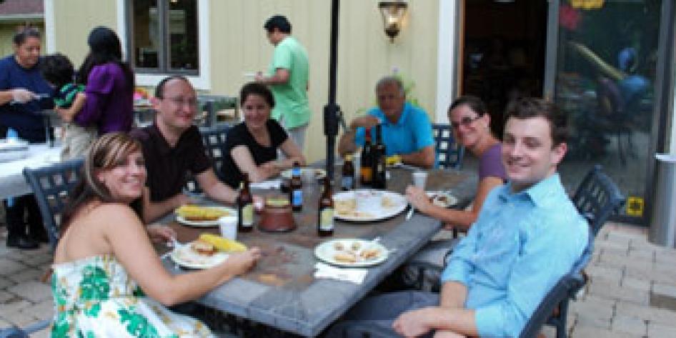 Annual vascular picnic, 2012 with six people having lunch outdoors around a table, with a serving table with three people in the background