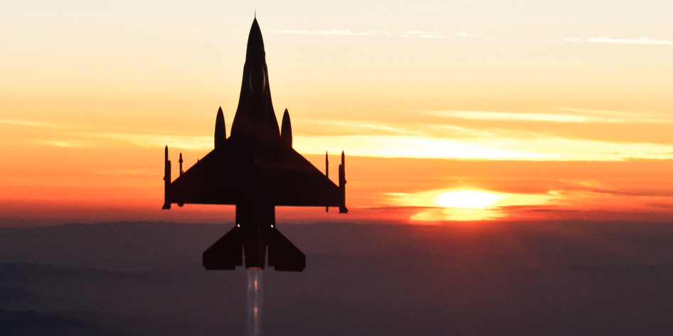 Fighter jet ascending against a sunet
