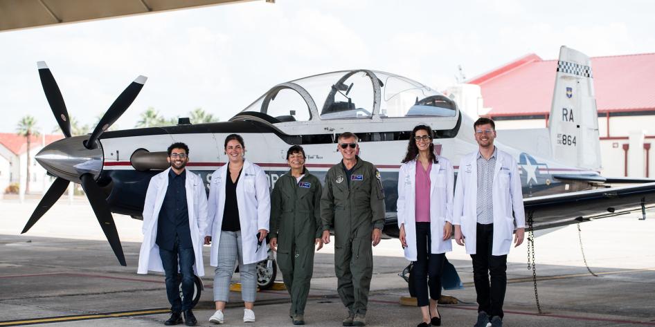 Dr. Decker and Dr. Damato (ret.) walking in front of a plane with students