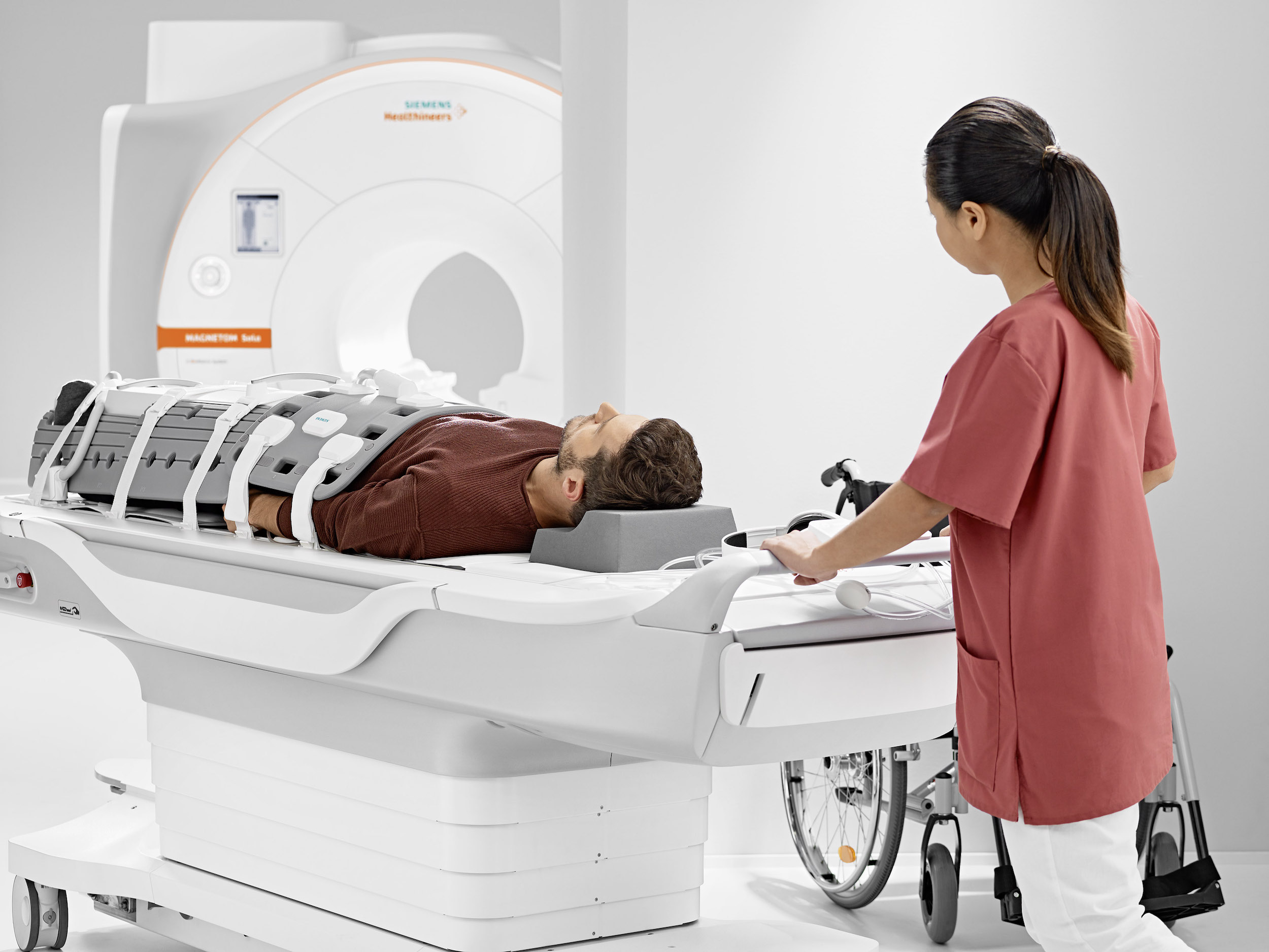 man on a gurney being pushed by a nurse toward an MRI machine
