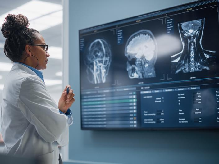 A Confident Black Female Neuroscientist looks at TV Screen with MRI Scan with Brain Images